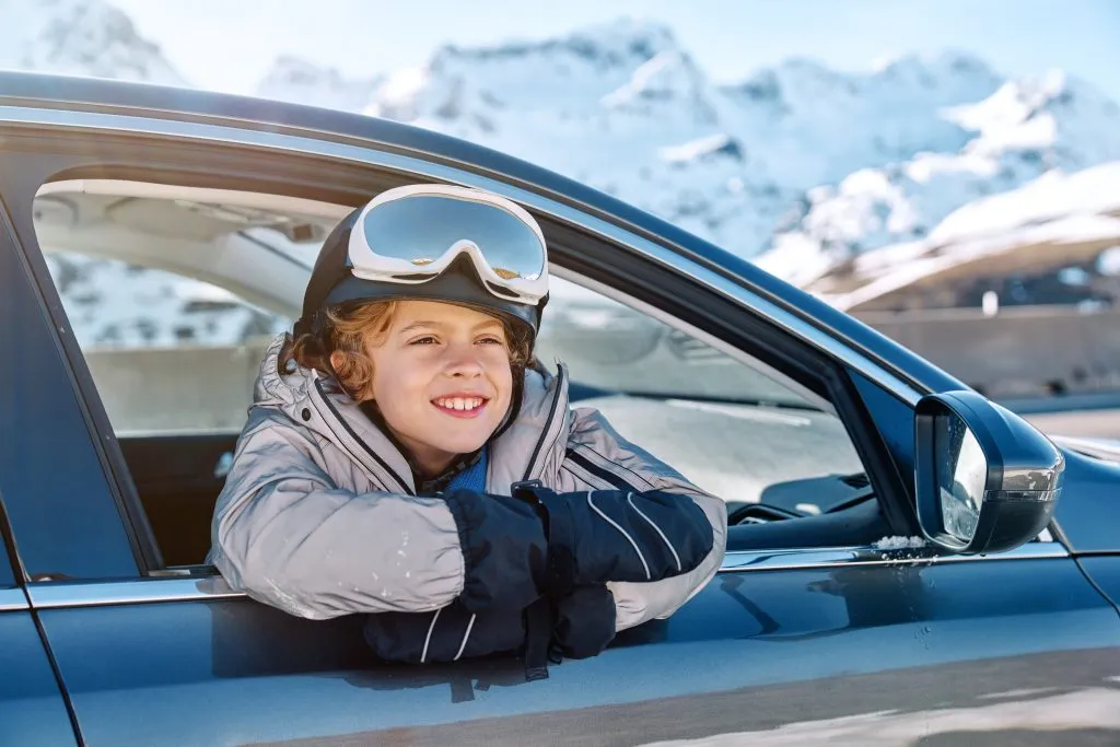 Cheerful boy in outerwear riding in car