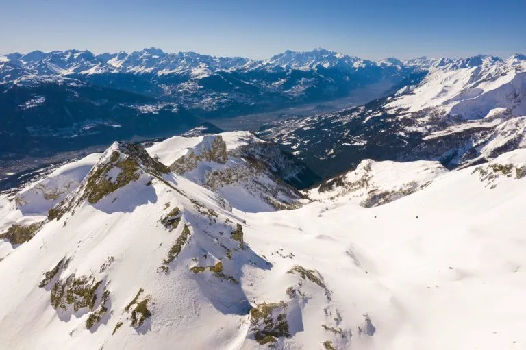 Aerial view of the Plaine Morte glacier at the top of the Crans Montana ski resort with a view on the Central Valais valley in the Swiss alps in Switzerland on a sunny winter day